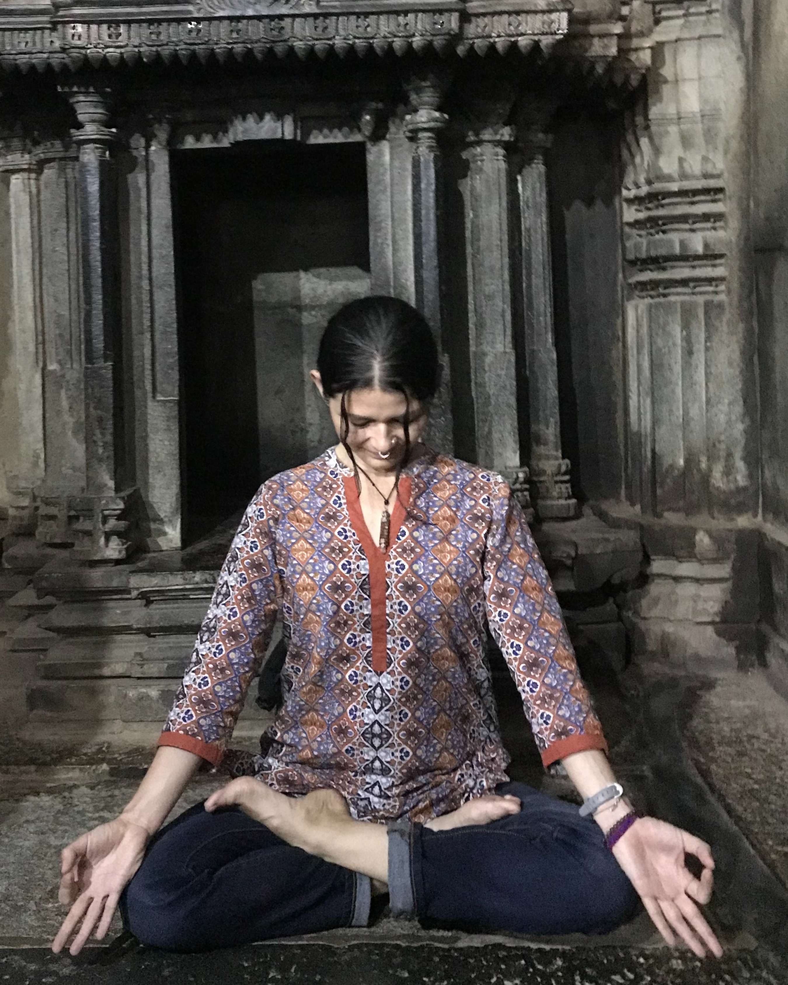 Karla Gómez en meditación frente a un templo de piedra en India